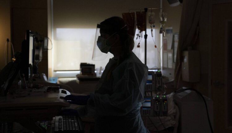 In this Nov. 19, 2020, file photo, registered nurse Virginia Petersen works on a computer while assisting a COVID-19 patient at Providence Holy Cross Medical Center in the Mission Hills section of LA. (AP Photo/Jae C. Hong)
