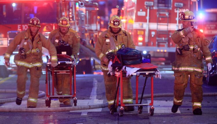 In this May 16, 2020, file photo, Los Angeles Fire Department firefighters push gurneys at the scene of a structure fire that injured multiple firefighters. (AP Photo/Damian Dovarganes)