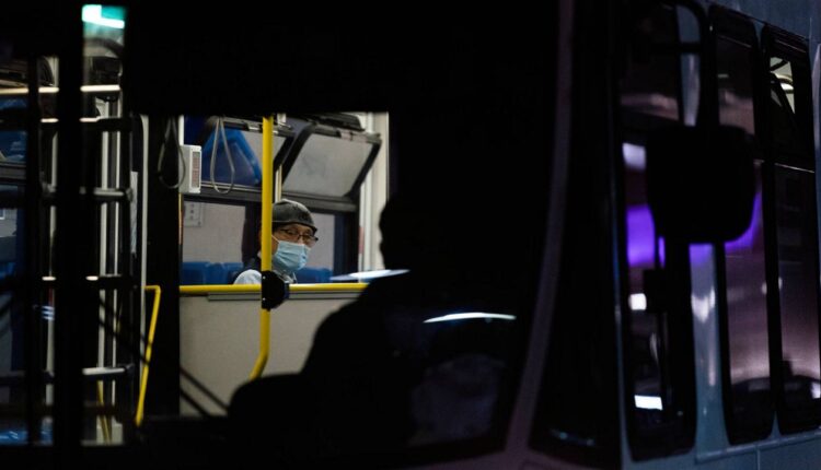 A traveler wearing a protective face mask sits in a shuttle bus at the Los Angeles International Airport, Nov. 30, 2021. (AP Photo/Jae C. Hong)