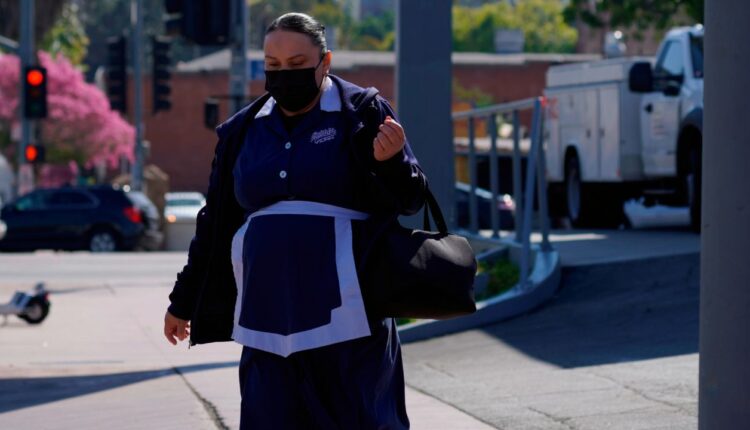 A Philippe The Original restaurant worker walks to her workplace in downtown Los Angeles, Monday, March 7, 2022. (AP Photo/Damian Dovarganes) 