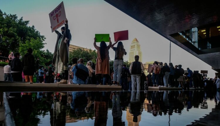 Demonstrators are reflected in a pond as they protest outside of the U.S. Courthouse in response to a leaked draft of the Supreme Court's opinion to overturn Roe v. Wade, in Los Angeles, March 3, 2022. (AP Photo/Ringo H.W. Chiu, File)