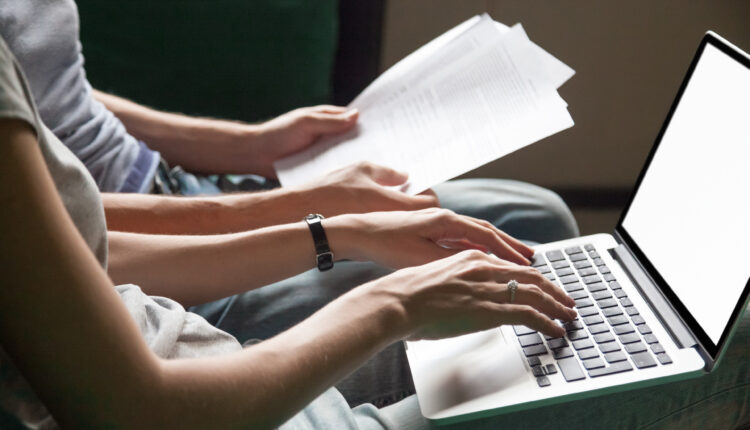 Close up of couple searching online information about legal document details with laptop, family studying important contract terms and conditions typing filling internet application form on website